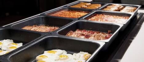 Un bufé con diversas opciones de comida, como huevos, carnes y otros platos.