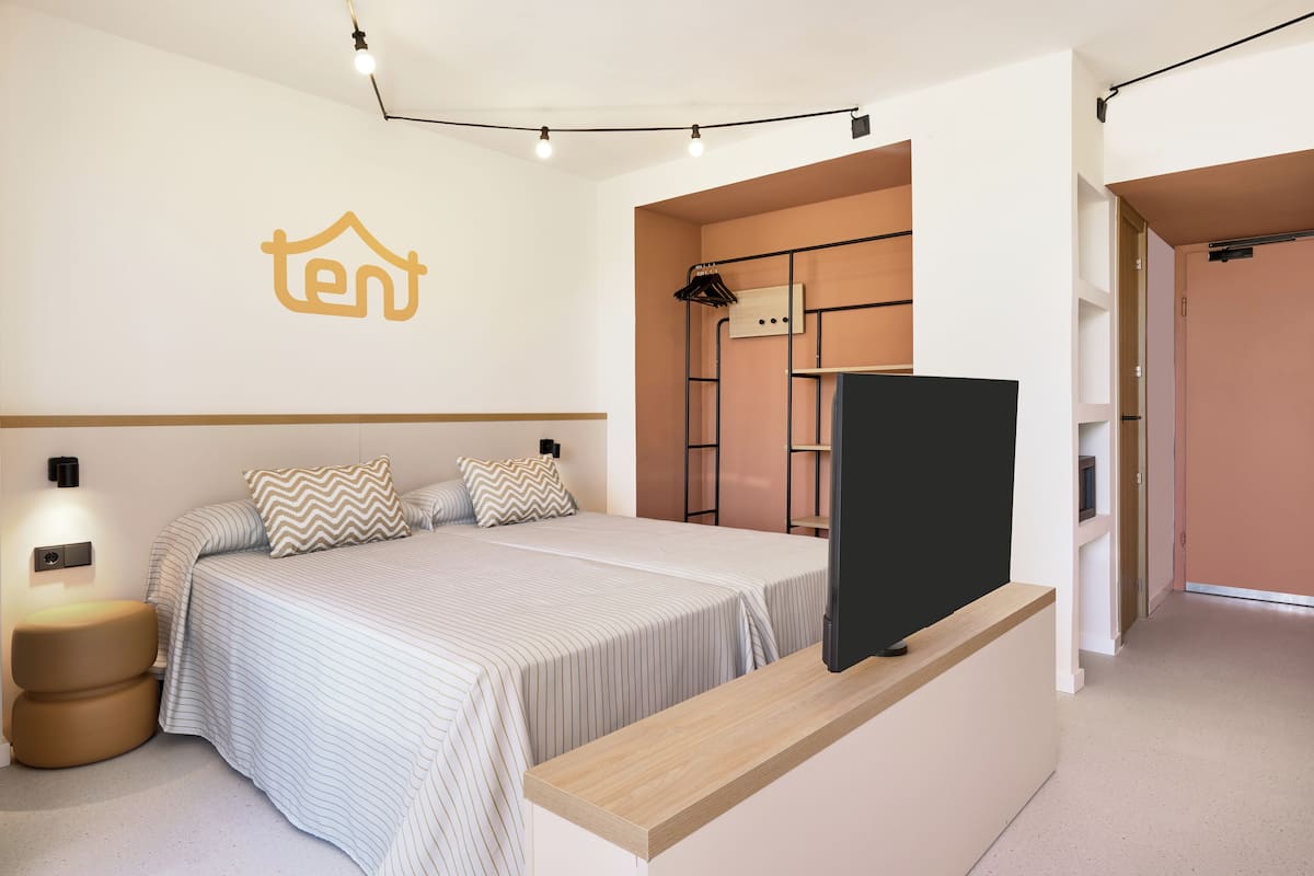 A bedroom with a bed, bedside table, and a TV on a stand.