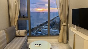 Uma sala de estar moderna com uma janela grande, uma televisão de tela plana, um sofá e uma mesa de centro.