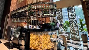 Uma área de bar com balcão circular, um lustre grande e piso xadrez.