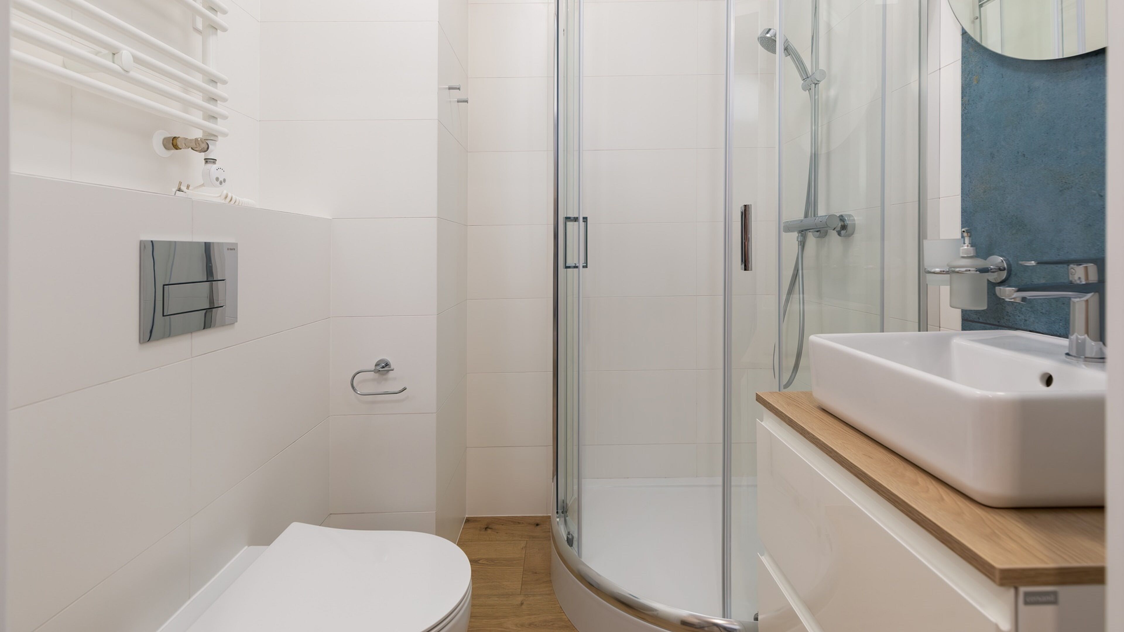 Un baño moderno con cabina de ducha de vidrio, inodoro blanco y lavabo con encimera de madera.