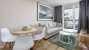 A modern, well-lit room with a sofa, a round table, and a television. - Apartamenty Sun & Snow Lighthouse (Trzebiatow)