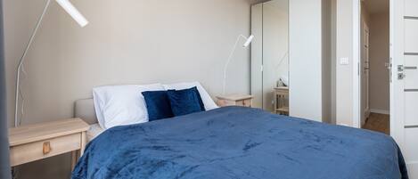 Un dormitorio con cama, mesitas de noche, armario y puerta.