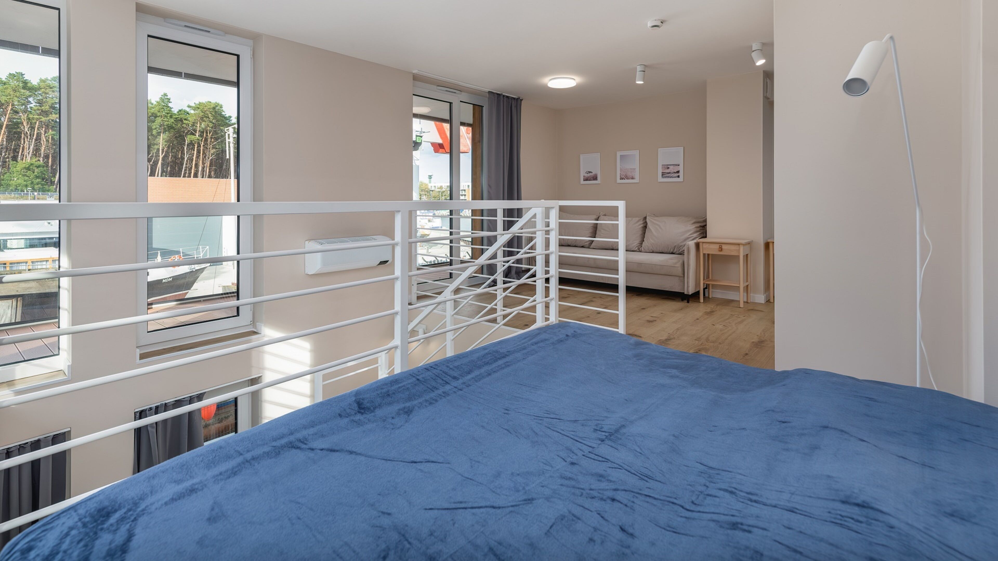 A modern hotel room with a large bed, a balcony with a view of the city, a sofa, and a small table.