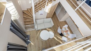A modern interior with a staircase, a sofa, a dining table with chairs, and a kitchen area. - Apartamenty Sun & Snow Lighthouse (Trzebiatow)