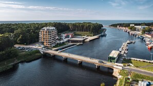 A modern bridge spanning a river with a marina and buildings on the opposite bank. - Apartamenty Sun & Snow Lighthouse (Trzebiatow)
