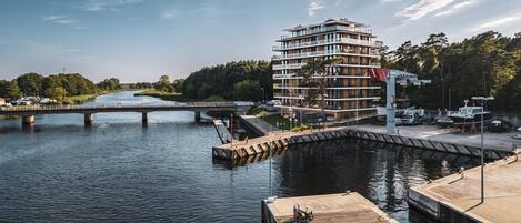 Un hotel moderno de varios pisos con vista al río, un embarcadero y un puente.