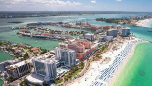 Un paisaje urbano costero con una playa, edificios altos y un puerto deportivo.