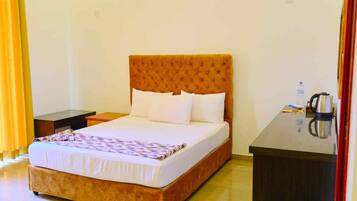 Habitación de hotel con una cama grande, una mesita de noche y un escritorio con hervidor.