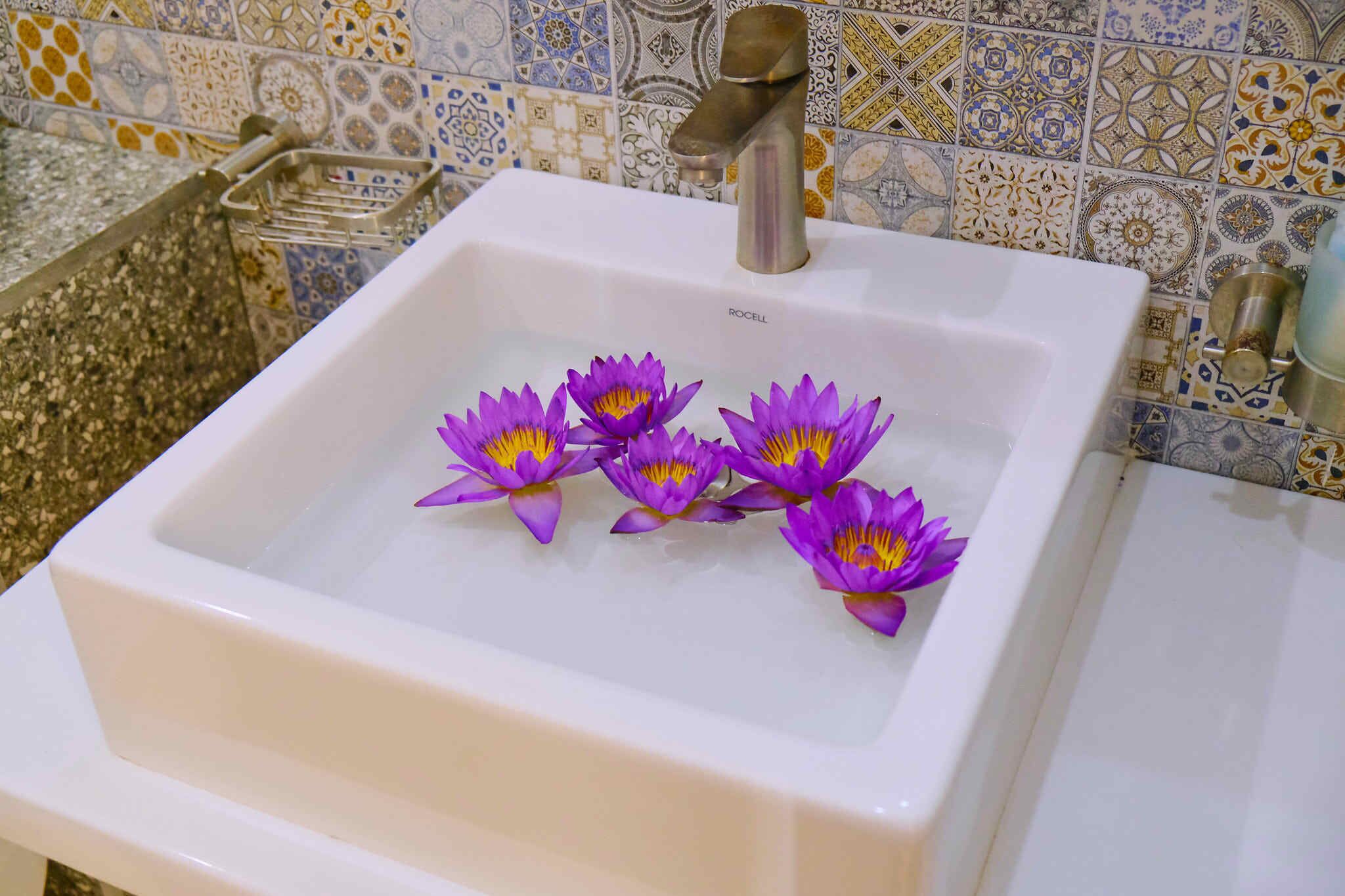 A bathroom sink with a decorative tile backsplash and a chrome faucet.