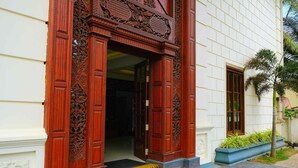 A building entrance with ornate wooden doors and a set of stairs leading up to it. - Polhena Grand Resort (Matara)