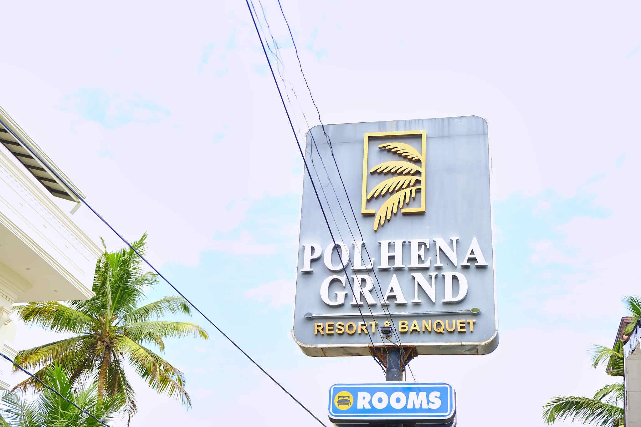 Un letrero para Polhena Grand Resort & Banquet con una palmera de fondo.