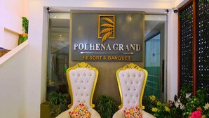 A reception area with a sign for Polhena Grand Resort & Banquet, featuring two ornate chairs with floral cushions. - Polhena Grand Resort (Matara)