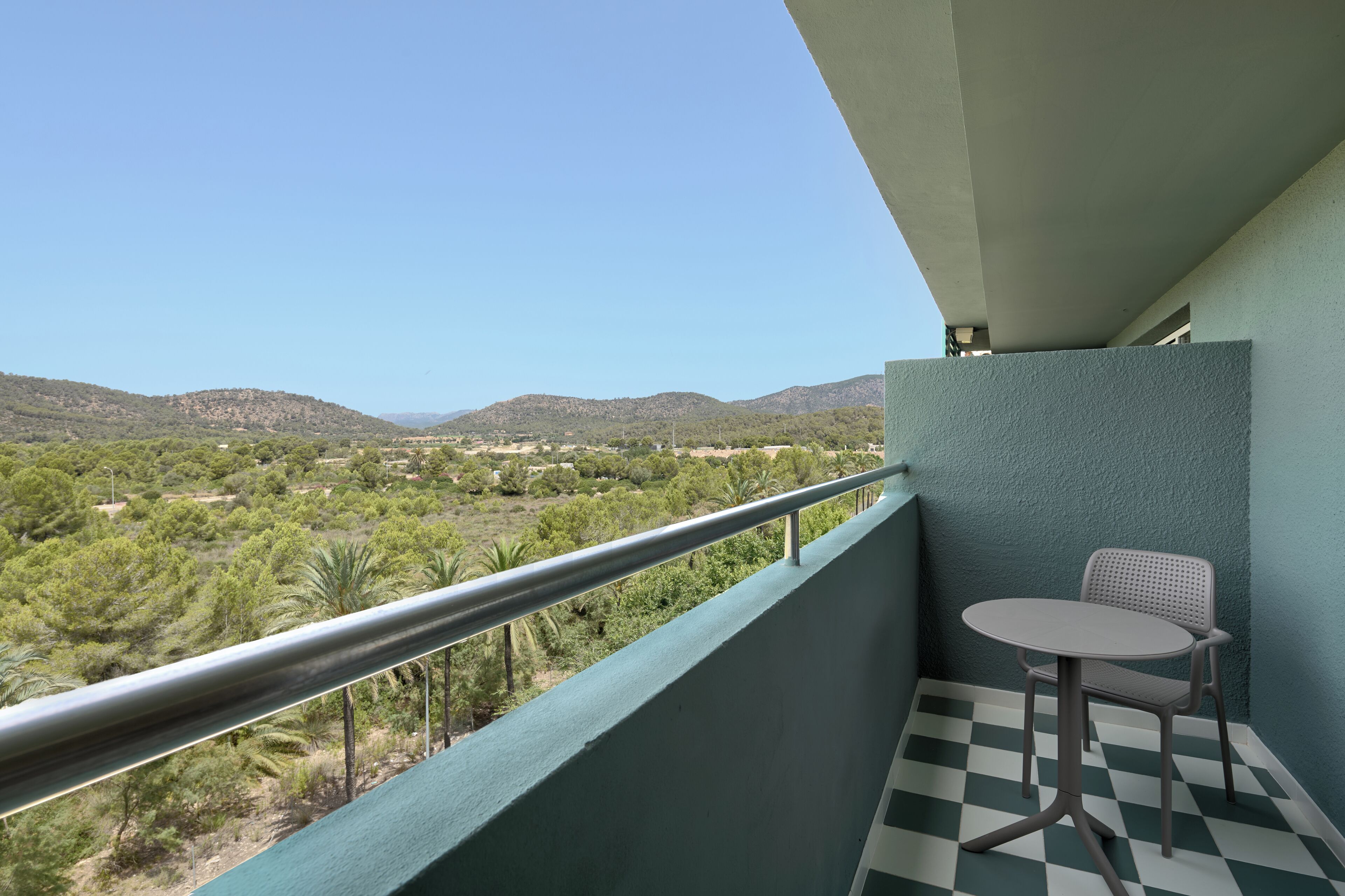 A balcony with a checkered floor, a table, and a chair.