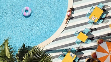 A pool area with a lounge chair and umbrella, a person relaxing by the pool, and a floating ring.