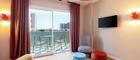 Een moderne hotelkamer met balkon, een flatscreen televisie en een plafondventilator.