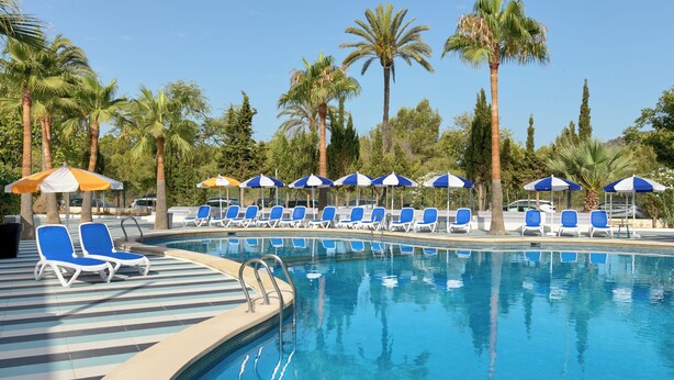 A pool area with blue lounge chairs and umbrellas, surrounded by palm trees. - tent Mojito Suites (Calvia)