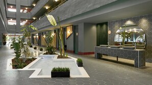 A modern lobby with a central water feature, potted plants, and a reception desk with a hexagonal tile wall. - tent Mojito Suites (Calvia)