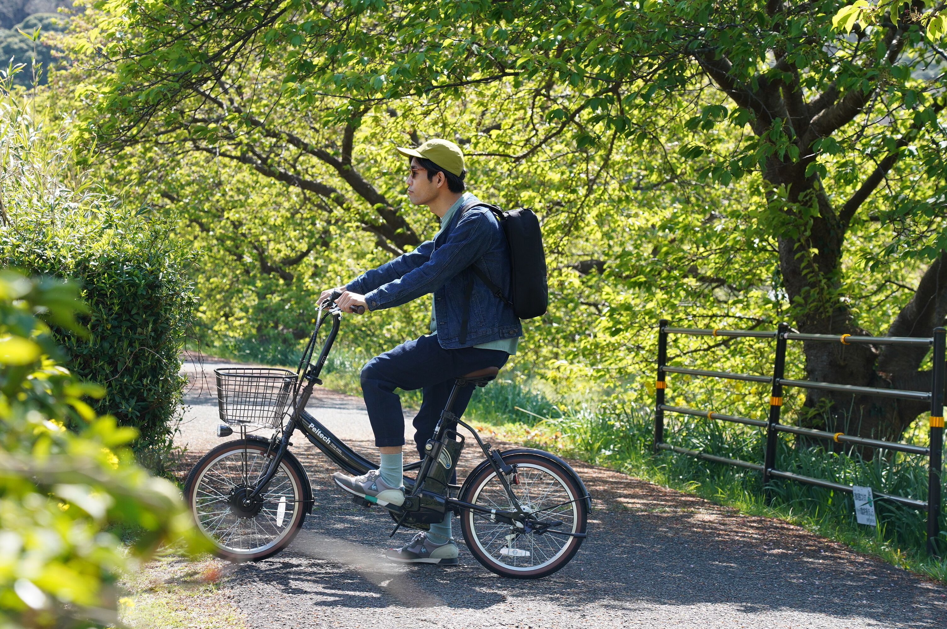 Una persona montando en bicicleta por un sendero pavimentado rodeado de vegetación.