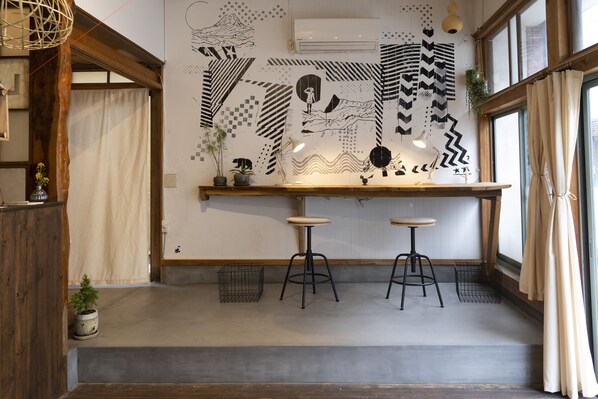 A modern kitchen with a wooden countertop, two stools, and a decorative wall with geometric patterns.