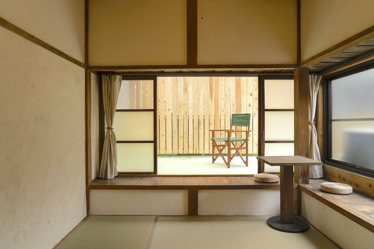 Ein traditioneller japanischer Raum mit Tatami-Böden, einem niedrigen Holztisch und einem grünen Stuhl.