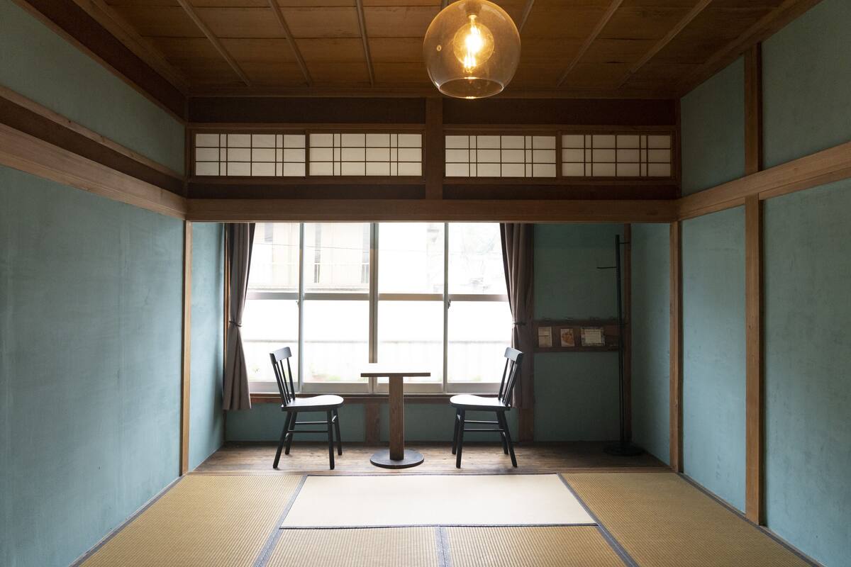 Ein traditioneller japanischer Raum mit Tatami-Boden, einem niedrigen Tisch und zwei Stühlen.