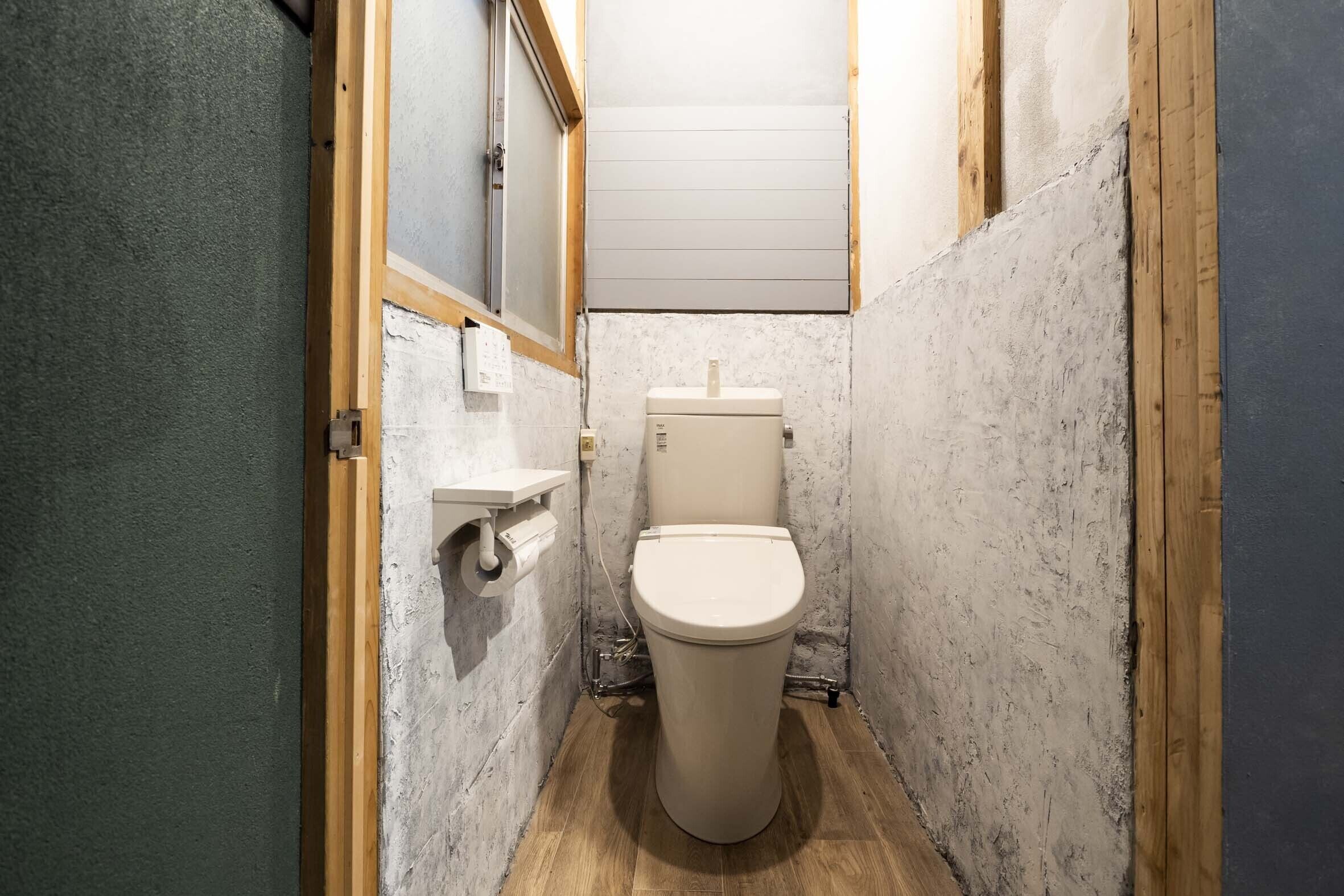 Un baño pequeño y estrecho con un inodoro, un marco de madera y una ventana.