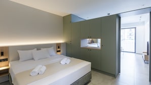 Ein modernes Hotelzimmer mit einem großen Bett, Nachttischen, einem integrierten Fernseher und einem Balkon mit Blick.