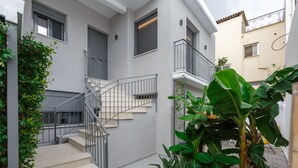 Ein Wohngebäude mit Treppe, Balkon und einer großen Pflanze.
