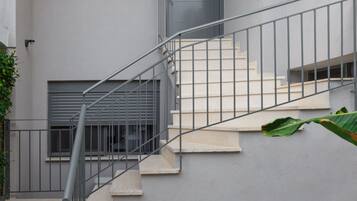A modern building with a grey exterior, a staircase with metal railings, and a door with a window above it.