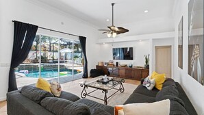A spacious living room with a large sofa, a coffee table, and a ceiling fan.