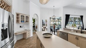 A modern kitchen with a large island, built-in appliances, and a dining area with a view.