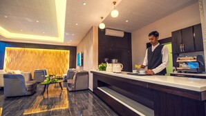 A modern hotel lobby with seating, a reception desk, and a coffee machine. - Suknai Aja Serviced apartments (Ha'il)