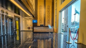 A modern hotel lobby with a reception desk, elevator, and a large window offering a view of the outside. - Suknai Aja Serviced apartments (Ha'il)