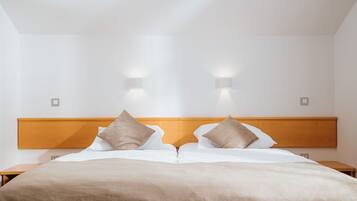 A hotel room with a large bed, two bedside tables, and wall-mounted lights.