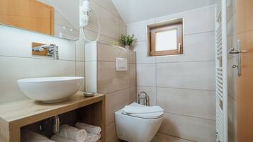Un baño moderno con un lavamanos grande de color blanco, un inodoro y una ventana pequeña.
