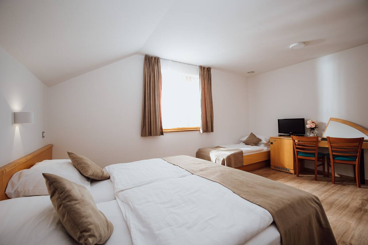 Una habitación de hotel con dos camas, un escritorio con computadora y televisión.
