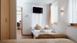 Une chambre d’hôtel moderne, équipée d’un lit, d’un téléviseur fixé au mur et offrant une vue sur le couloir.