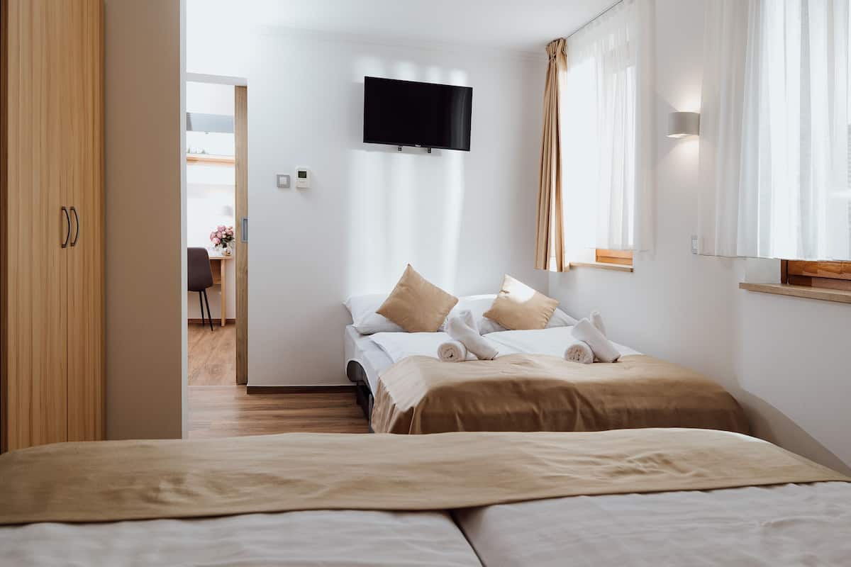 Una habitación de hotel moderna con una cama, un televisor montado en la pared y vista al pasillo.
