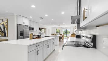 A modern kitchen with white cabinetry, stainless steel appliances, and a central island.