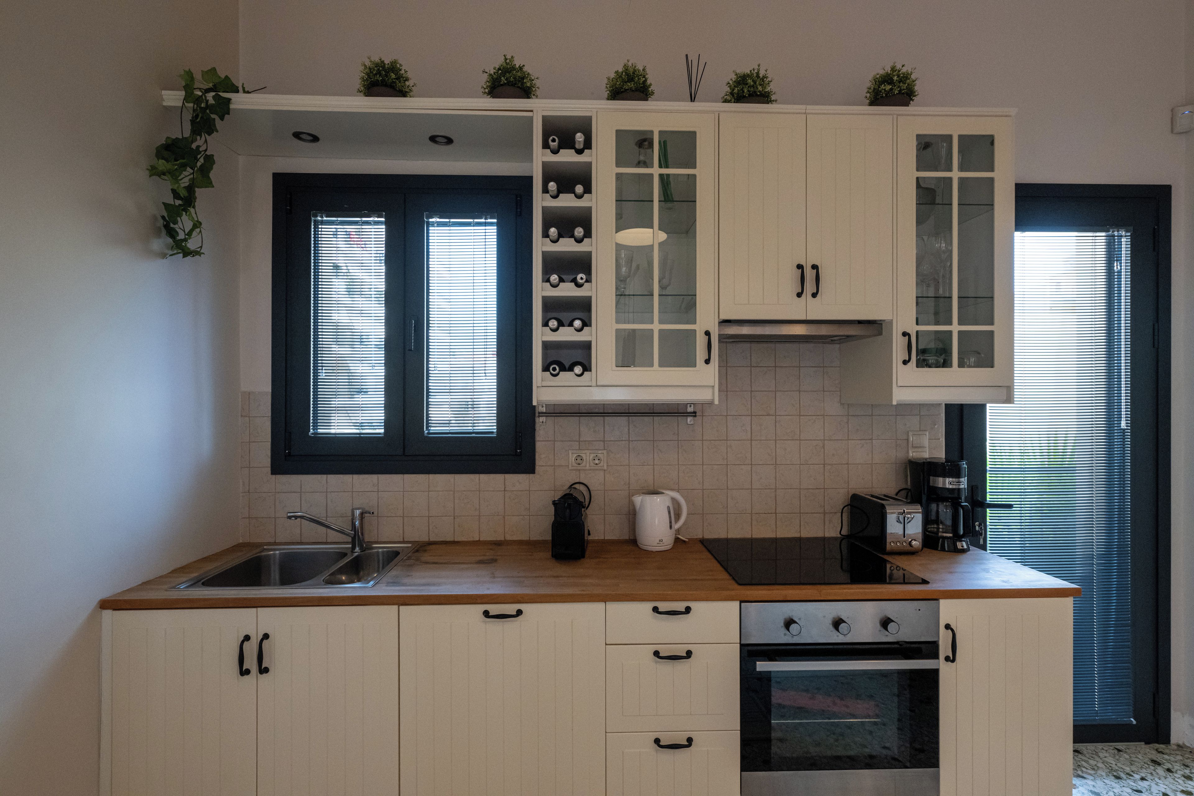 Eine Küche mit Spüle, Herd, Schränken und einem Fenster mit Jalousien.