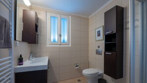 A bathroom with a toilet, sink, and dark wooden cabinets. - Angelinas Quarters - Kalamata Mediterranean Villas
 (Kalamata)