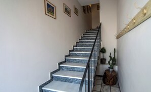 A staircase with marble steps and a metal railing, leading to a landing with a potted plant and a wooden stool. - Angelinas Quarters - Kalamata Mediterranean Villas
 (Kalamata)