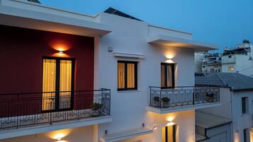 A modern two-story building with balconies, exterior lighting, and a red facade.