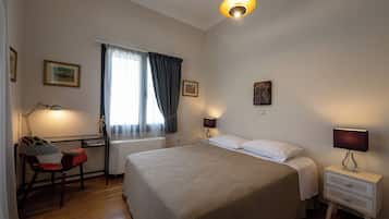 Ein Schlafzimmer mit einem großen Bett, einem Schreibtisch mit Stuhl, einem Fenster mit Vorhängen und zwei Nachttischlampen.