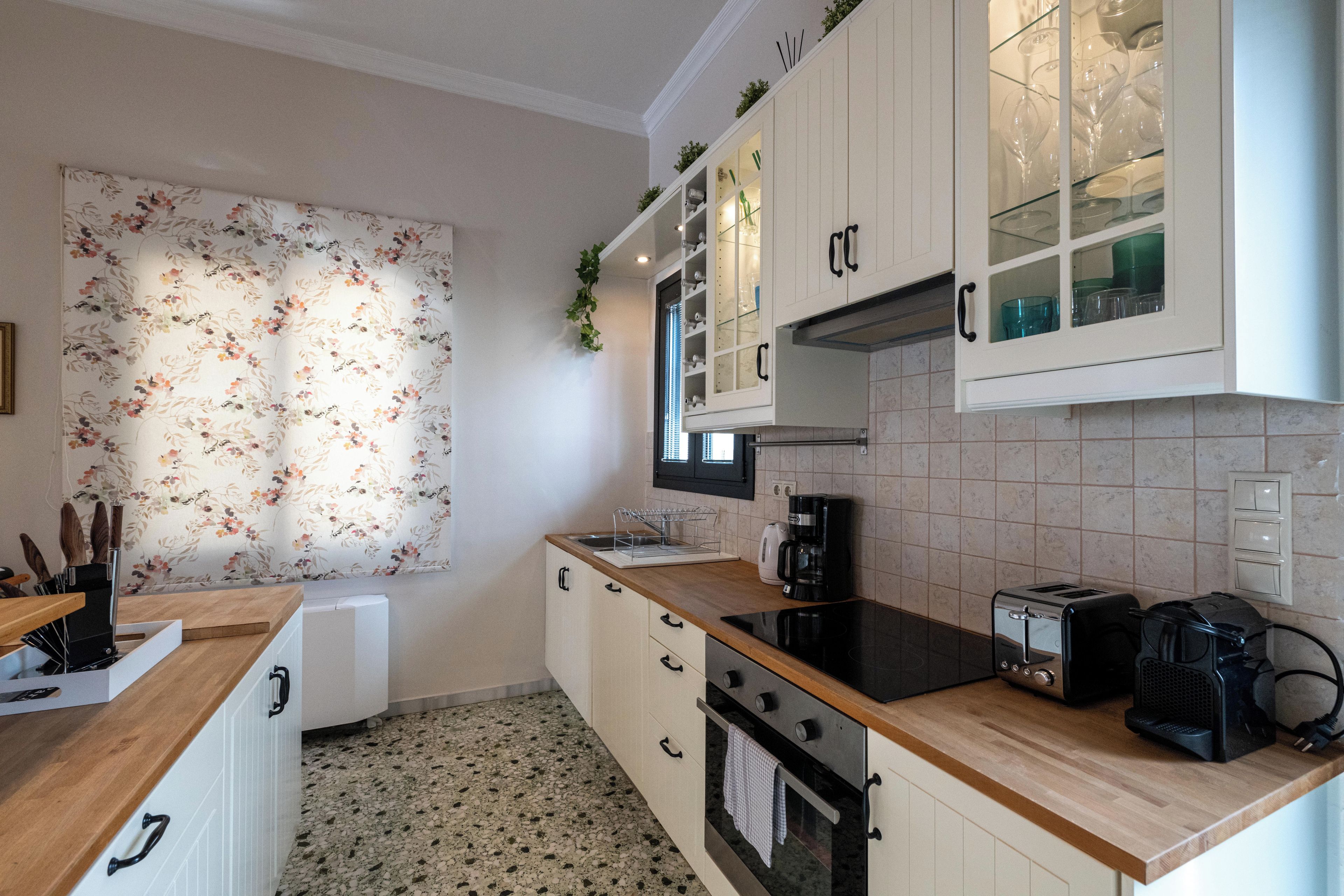 A kitchen with white cabinets, a wooden countertop, a stove, a toaster, and a coffee maker.