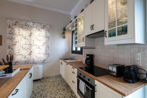 A kitchen with white cabinets, a wooden countertop, a stove, a toaster, and a coffee maker.