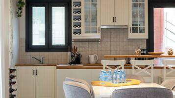 Una cocina moderna con armarios blancos, encimera de granito y zona de comedor con sillas grises.