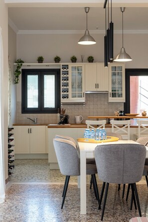 Une cuisine moderne avec des meubles blancs, un plan de travail en granit et un coin repas doté de chaises grises.
