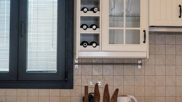 A kitchen with white cabinets, a wine rack, and a window with blinds.